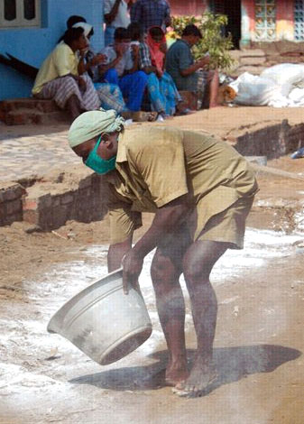 A government worker applies a bleaching agent to the street in India to help prevent the spread of disease.  Image credit:  MSNBC.com